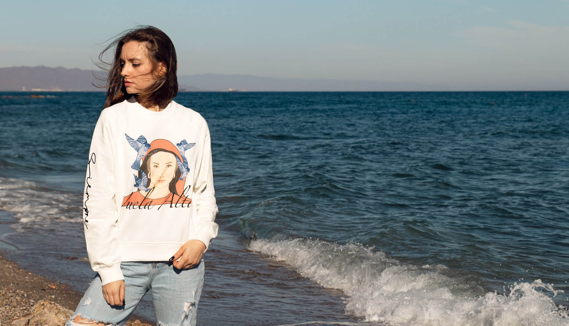 Chica posando en la playa con una prenda de la marca Siempre Viva
